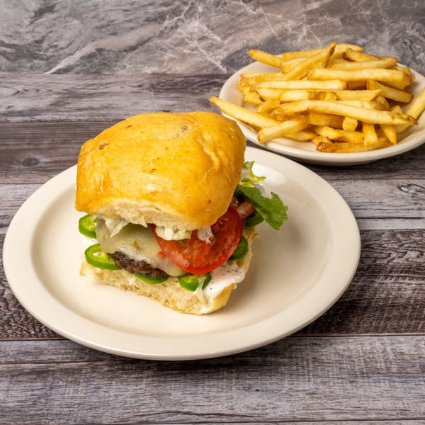 A burger with melted cheese, tomato, lettuce, and jalapeños, served with a side of fries.