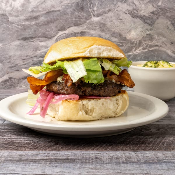 Gourmet burger with bacon, lettuce, pickled onions, and a side of macaroni and cheese.